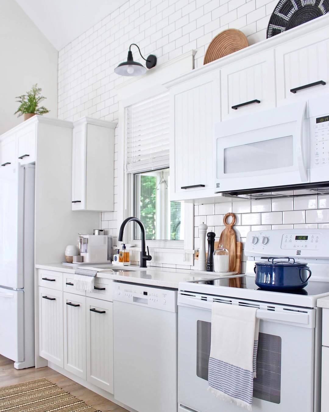 черный смеситель и ручке кухонных шкафов на белой кухне